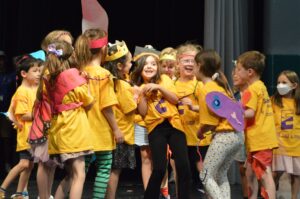 on stage, camp, elementary, encore shirts, yellow encore shirts, dragon, knight, props, crown, smiling